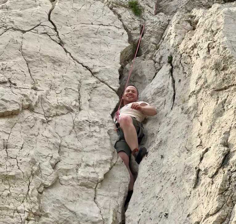 Grimpeur encordé progressant dans une fissure rocheuse en extérieur